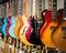 Row of acoustic and electric guitars different color in a music instruments shop