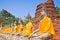 A row of ancient buddha statues in front of ruin pagoda