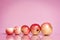 A row of apples of different sizes on a pink background with place for text