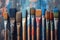 Row of artist paintbrushes closeup on artistic wooden background. Brushes with colorful paints