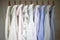 A row of assorted business shirts for women on hangers in a closet