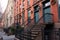 Row of Beautiful Old Brick Homes in Chelsea of New York City with Staircases and Christmas Wreaths along an empty Sidewalk