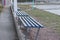 A row of blue wooden benches stand on the gray ground