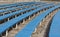 Row of blue wooden seats on a spectator grandstand photo. Bench in the park