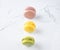 Row of bright colored macaroons on marble background