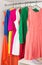 Row of bright colorful dress hanging on coat hanger, shoes