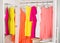 Row of bright colorful dress hanging on coat hanger, shoes and h