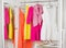 Row of bright colorful dress hanging on coat hanger, shoes and h