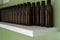 Row of brown capped plastic bottles on a shelf with a green background. Room for copy space or text. Organised in a neat row,