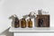 A row of brown small pharmacy bottles instead of vases with branches of blossoming cotton and wooden boxes on a white surface of