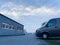 Row of brown transportation delivery vans being parked in front of warehouse