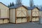 A row of brown wooden stalls stand on gray asphalt