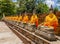 Row of Buddha statues with orange robes in Ayutthaya old Temple