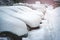 A row of cars standing in the parking lot covered with a thick layer of snow.