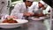 Row of chefs garnishing spaghetti dishes