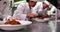 Row of chefs garnishing spaghetti dishes