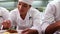 Row of chefs garnishing spaghetti dishes with basil leaf