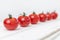 Row of cherry tomatoes on a white wooden table. Vegetarianism and a healthy lifestyle. Side view