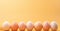 A row of chicken eggs in varying shades of white to peach against a yellow background, suitable for culinary and