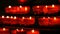 Row of christian prayer red round votive candles burn in the dark. Prayer lighting Sacrificial Candles close up. Burning