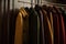 a row of coats hanging on a rack in a closet with a coat rack in the background and a coat rack in the foreground