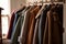 a row of coats hanging on a rail in a room with a window and a lamp in the background and a coat rack in the foreground