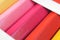 A row of colored pencils close-up that lie in a cardboard box. Yellow, pink, orange. Bright vivid illustration on the theme of