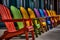 A row of colorful adirondack chairs are lined up outside. AI generation