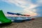 A row of colorful catamarans with canopies stand on the beach near the sea in the background of the setting sun in summer