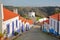 A row of colorful houses along a steep cobbled street inside Odeceixe near Aljezur, leading to a whitewashed traditional windmil