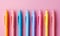 A row of colorful pens on pink and pastel color background.