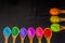 a row of colorful powder colors on wooden spoon in black background