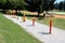 Row of colorful red and yellow outdoor public park fitness exercise equipment in various shapes surrounded with gravel and grass