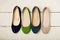 Row of colorful shoes ballerinas on a white wooden background.