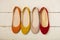 Row of colorful shoes ballerinas on a white wooden background.