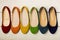 Row of colorful shoes ballerinas on a white wooden background.