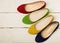 Row of colorful shoes ballerinas on a white wooden background.