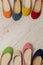 Row of colorful shoes ballerinas on a white wooden background.