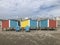 Row of colorful wooden changing rooms and chairs on the beach