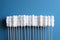 A row of cotton swabs on wooden sticks on a blue background