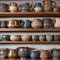 A row of decorative, handcrafted ceramic mugs on a shelf in a pottery shop2