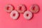 Row of donut on pimk background. Photo of sweets. Top view.