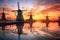 row of dutch windmills at sunset with reflections