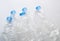 Row of empty deformed clear plastic water bottles with blue lid on white background