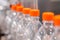 Row of empty pet lemonade bottles with orange caps on conveyor belt - close up