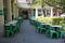 A row of empty tables and chairs line the sidewalk at an outdoor cafe