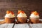 Row of fall pumpkin spice cupcakes with creamy frosting against rustic wood