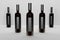 Row of five dark glass bottles with black blank labels