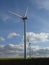 Row of five wind turbines in a blue sky with cottony clouds