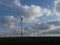 Row of five wind turbines surrounded by cottony clouds